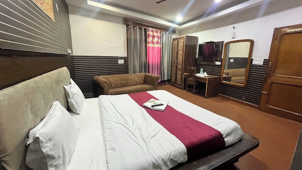 Een hotelkamer met een groot bed, een bank, een bureau, een televisie en een kledingkast.