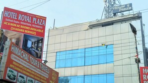 Een hotel genaamd 'Royal Plaza' met een bord waarop 24-uurs service en kamers mét en zonder airconditioning worden aangeboden.