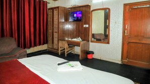 Een hotelkamer met een bed, bureau, televisie en spiegel.
