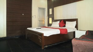 Een hotelkamer met een houten bed, een nachtkastje en een rood-wit kussen.