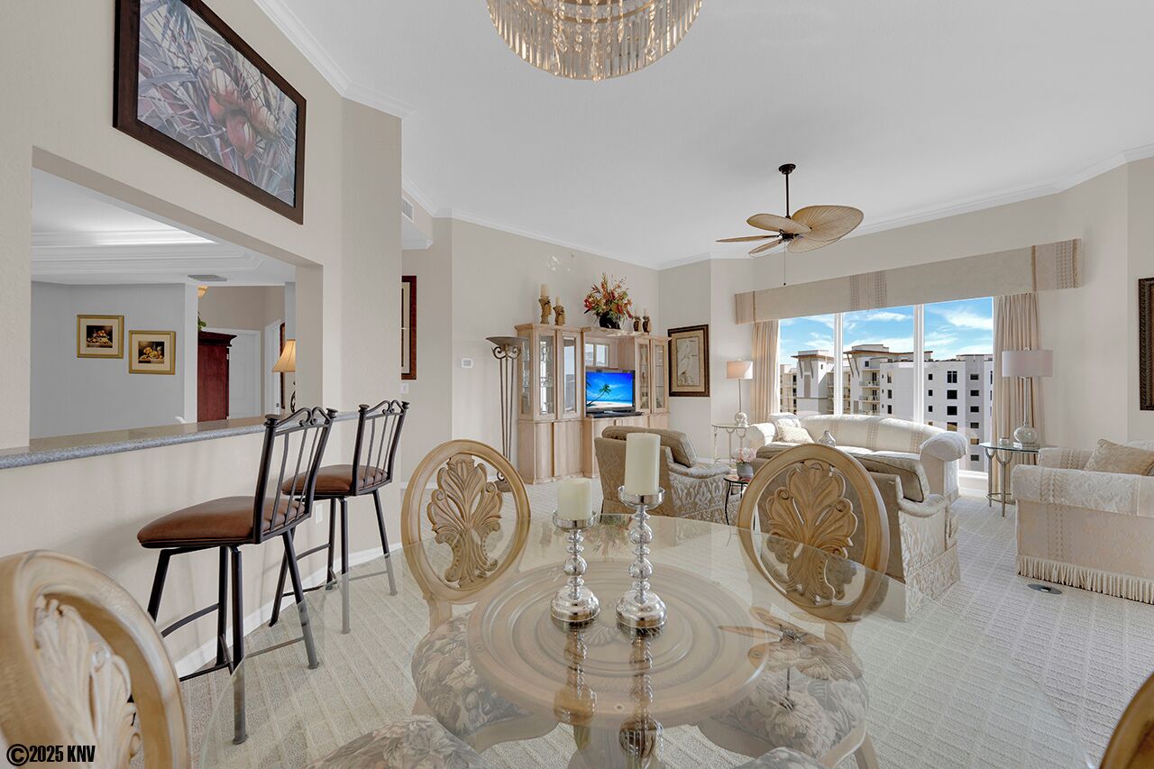 A spacious living room with a large TV, comfortable seating, and a dining area with a glass table.