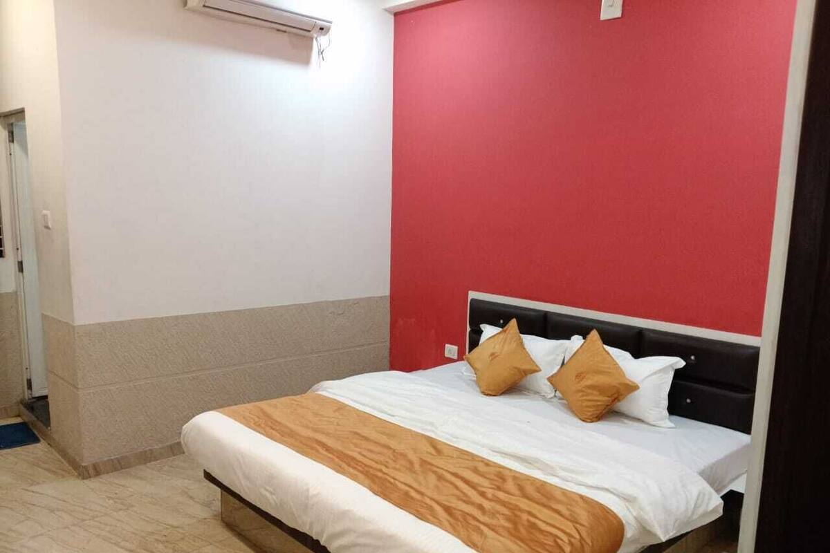 Une chambre d’hôtel avec un lit, un mur d’accent rouge et un plafond blanc.