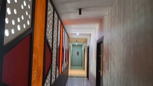 Un pasillo con piso pulido, un extintor de incendios en la pared y una puerta a la derecha.