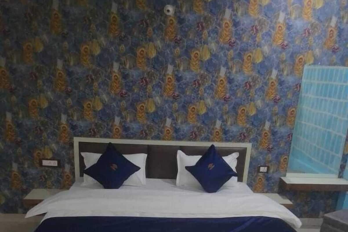 Une chambre à coucher avec un lit, deux oreillers, une tête de lit et un mur décoré d’un motif.