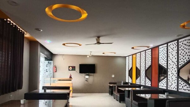 Un restaurante moderno con una barra alargada, varias zonas de estar y un ventilador de techo.