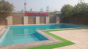 Zona de piscina de un hotel, con un cartel que dice 'HOTEL HOLIDAYS'.