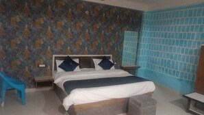 Un dormitorio con cama, mesita de noche, una silla azul y pared de azulejos.