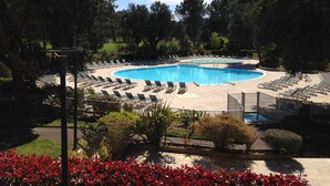 Une piscine avec des chaises longues et un jardin aménagé autour.