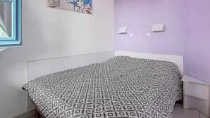 Une chambre à coucher avec un lit, une fenêtre, une œuvre d’art accrochée au mur et un interrupteur.