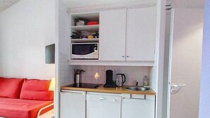 Une petite cuisine équipée d’un four à micro-ondes, d’une machine à café et d’un évier.