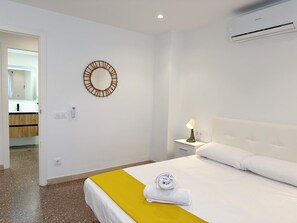 Ein Hotelzimmer mit Bett, Nachttischlampe, Spiegel und Klimaanlage.