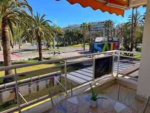 Ein Balkon mit Blick auf eine Straße, Palmen und ein Gebäude mit einem großen 'SA'-Schild.