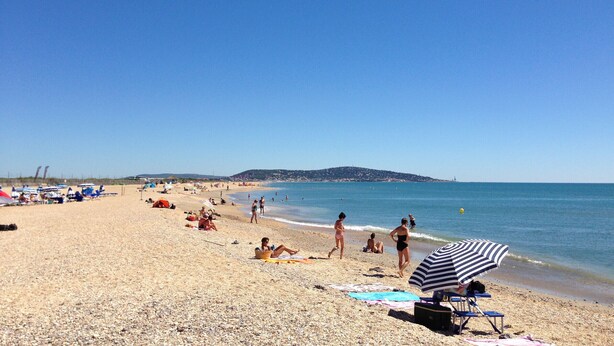 A beach with people sunbathing and swimming, a clear sky, and a distant hill. - Two-room apartment in Sète - Terrace, Parking, WiFi (Sète)