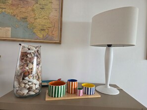 Un mapa, una lámpara y un frasco con conchas marinas sobre una mesa.
