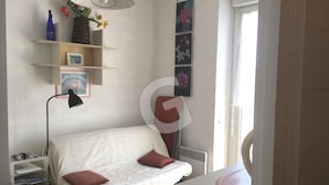 A small, neatly arranged bedroom with a single bed, bedside table, and a desk. There are shelves with decorative items and a radiator. - Cozy studio downtown near the beach (La Tranche-sur-Mer)