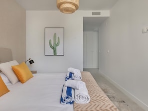A hotel room with a bed, pillows, a framed cactus artwork, and a neatly made bed with towels. - Modern Apartment in Estepona - 3 Bedrooms, Near Beach (Estepona)