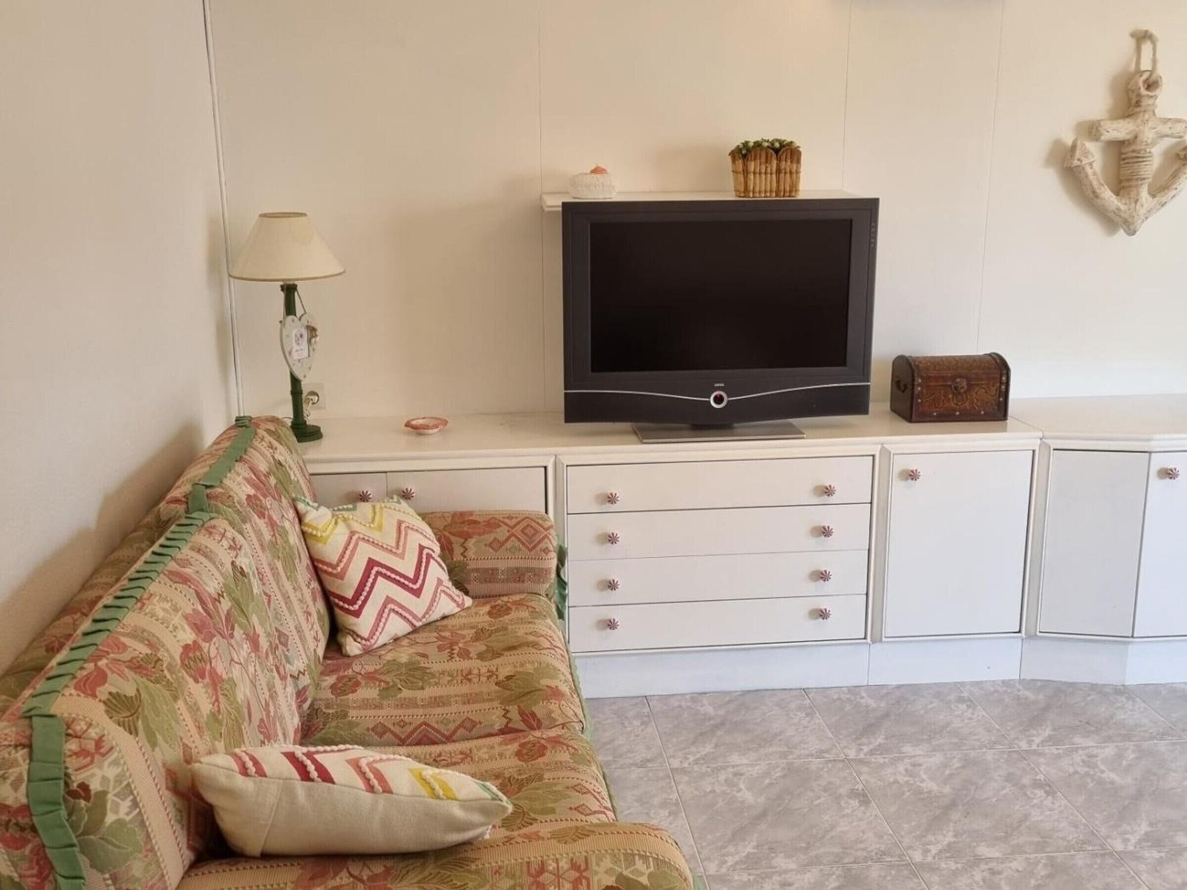 A living room with a sofa, television, and cabinets.