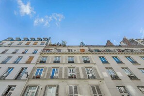 Ein mehrstöckiges Gebäude mit einer Reihe von Fenstern und Balkonen, unter blauem Himmel.