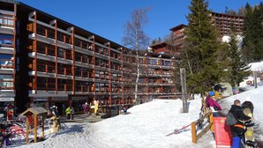 Un hotel a più piani con una stazione sciistica sullo sfondo.