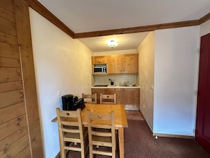 A compact kitchen with wooden cabinets, a microwave, and a coffee maker on the counter. - Apartment for 4, ski-in/ski-out with balcony, parking included (Lanslebourg-Mont-Cenis)
