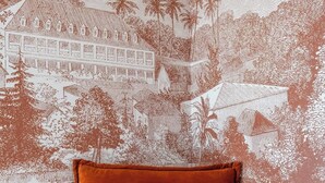 A bed with a textured orange cover, set against a wall with a detailed mural of a tropical landscape. - Near Paris - 25 minutes from Eiffel Tower (Issy-les-Moulineaux)