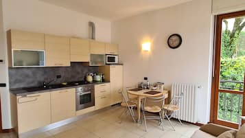 Une cuisine moderne avec un coin repas, une horloge au mur et une vue sur la verdure à l’extérieur.