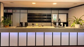 A modern reception area with a counter, a reception desk, a BMZ sign, and a fire alarm. - Roomie Hotel (Schriesheim)