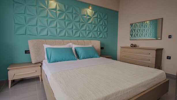 Un dormitorio moderno con una cama grande, dos mesitas de noche, una mesilla, un aparador y un panel decorativo en la pared.
