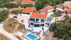 Vista aérea de una casa moderna de dos pisos con piscina, rodeada de otras edificaciones residenciales.