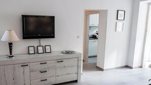 Un salon moderne avec un téléviseur à écran plat, une lampe et un meuble en bois doté de tiroirs.