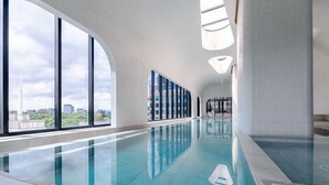 An indoor swimming pool with large windows and a city view. - Luxe City Family Suite | Heated Pool & Gym (Melbourne)