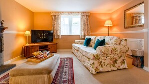 A living room with a sofa, a television, a lamp, and a tray with snacks. - New Cross Keys House - Cosy 4-bed Cottage in Kirk Yetholm (Kelso)