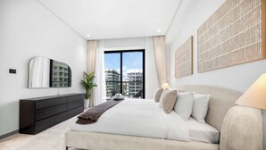 A modern bedroom with a large bed, a dark dresser, a bedside table, and a city view through the window. - Stayshort - 1 Bed in JGC Sleeps 4 With Balcony (Dubai)
