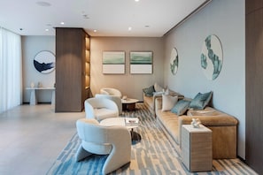 A modern living room with a sofa, armchairs, a coffee table, and artwork on the walls. - One Lux Stay 2BR Downtown View Grande Signature Residences (Dubai)