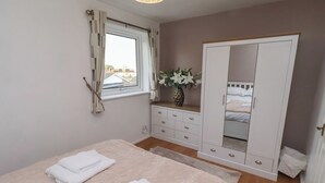 Un dormitorio con cama, armario, ventana y espejo.