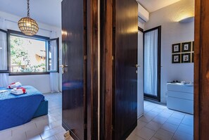 A hotel room with a bed, a wardrobe, a bedside table, a window with a view, and a hanging light fixture. - Il Vecchio Faro Carolina (Loiri Porto San Paolo)