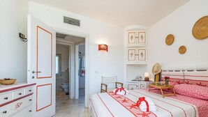 A bedroom with a bed, bedside tables, a wardrobe, and a bathroom visible through an open door. - Apposentu (Case Peschiera-Lu Fraili)
