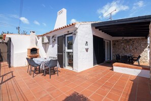A patio with a table and chairs, a brick oven, and a stone wall. - Villa Lotus with Private Pool and Air Conditioning (Albufeira)
