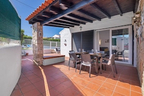 An outdoor patio with a stone column, a covered seating area, and a dining table with chairs. - Villa Lotus with Private Pool and Air Conditioning (Albufeira)