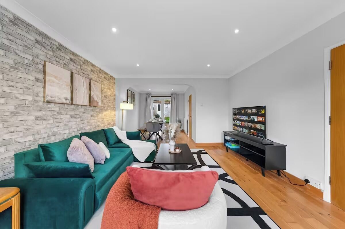 Ein modernes Wohnzimmer mit einem grünen Sofa, einem Couchtisch und einem Fernseher auf einem Schrank.