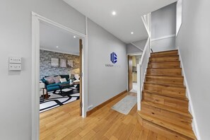 Un interno moderno con una scala, un'area living con divano e tavolino, e un logo sulla parete.