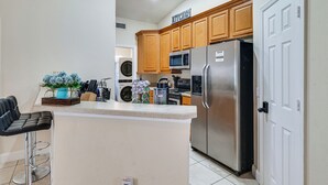 A kitchen with wooden cabinets, a stainless steel refrigerator, a microwave, and a sink. - Pool Access, 7 Mi to Disney: Family Getaway! (Davenport)