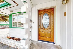 Uma casa com porta de madeira, janela verde e fachada branca.