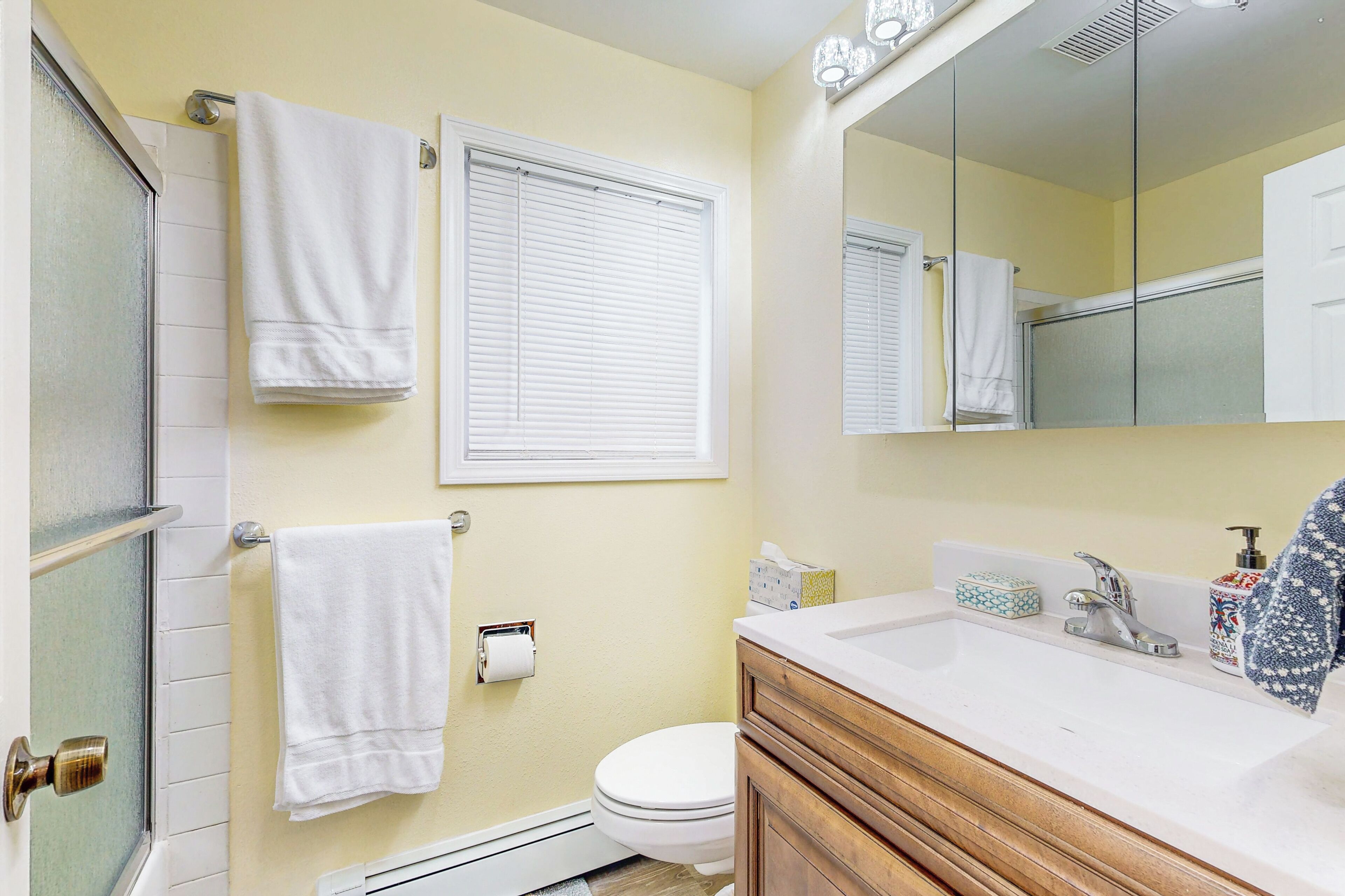 A bathroom with a toilet, sink, mirror, and towel rack.