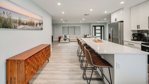 Une cuisine moderne dotée d’un grand îlot central, de tabourets de bar et d’un coin repas avec un canapé.