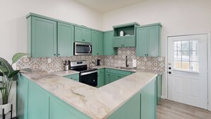 A kitchen with teal cabinets, a marble countertop, and a microwave. - 2 BR Home one Block From Botanical Gardens (San Antonio)