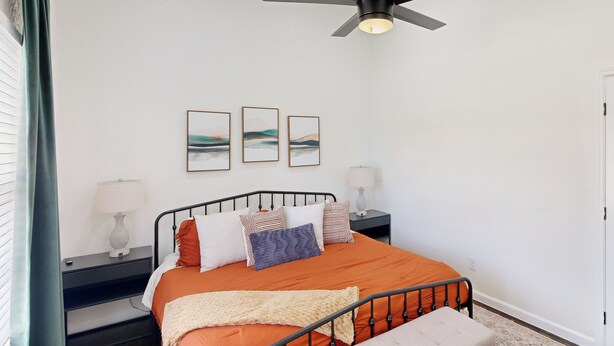 A bedroom with a bed, bedside tables, a ceiling fan, and artwork on the wall. - 2 BR Home one Block From Botanical Gardens (San Antonio)