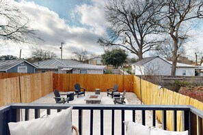 Ein Garten mit einer Holzterrasse, einer Sitzgelegenheit im Freien und einem Kamin aus Stein.