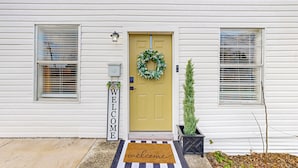 A white house with a yellow door, a welcome sign, and a wreath. - 2 BR Home one Block From Botanical Gardens (San Antonio)