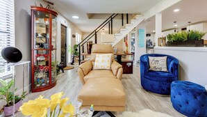 A modern living room with a sofa, a blue armchair, and a glass cabinet. - 10 Mi to Public Beaches: Port St Lucie Getaway (Port Saint Lucie)